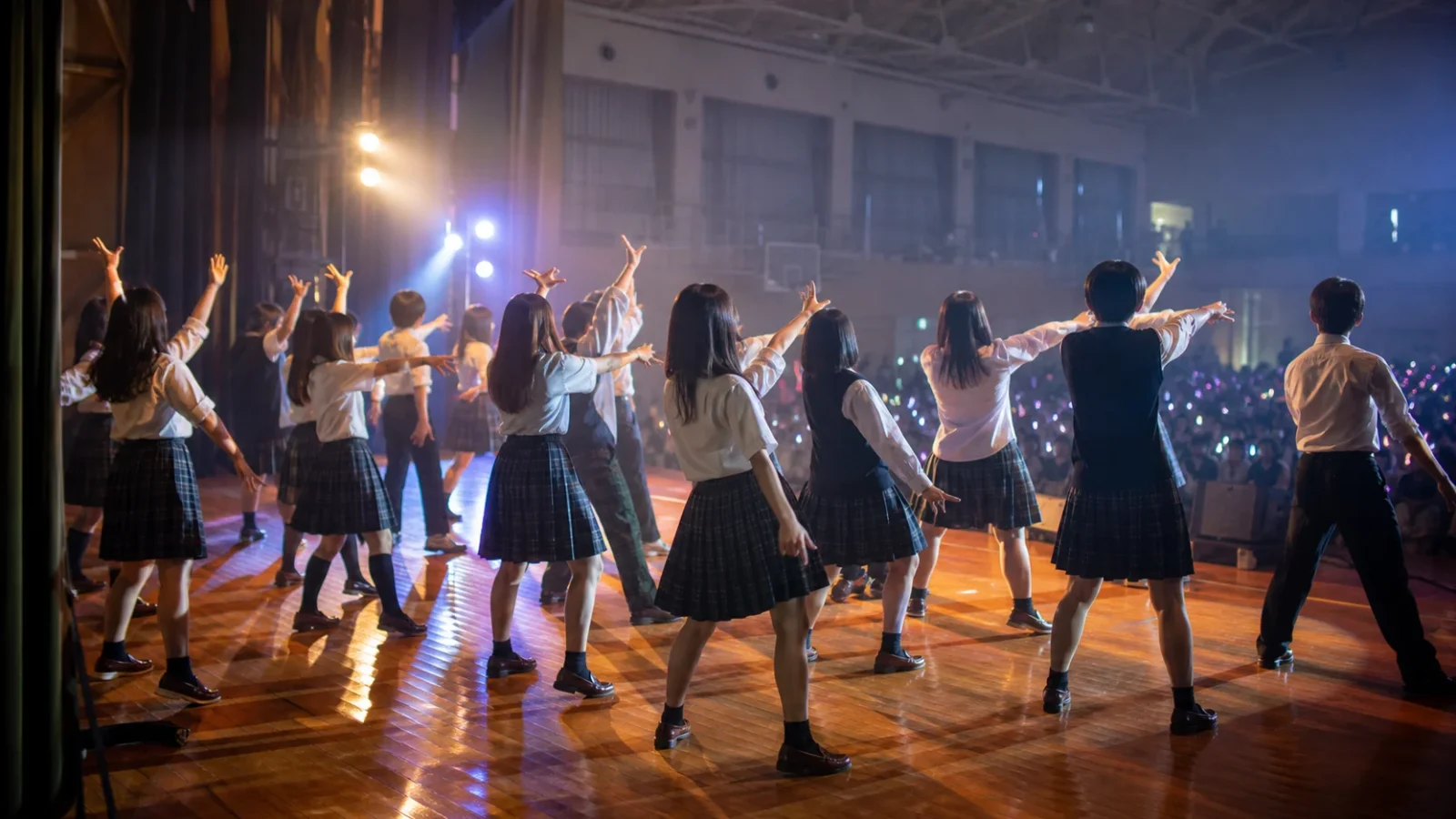 文化祭で盛り上がるダンス曲 - 体育館のステージで踊る学生たちの後ろ姿のシルエットと客席の光。青春の熱気。顔・文字・ロゴなし。